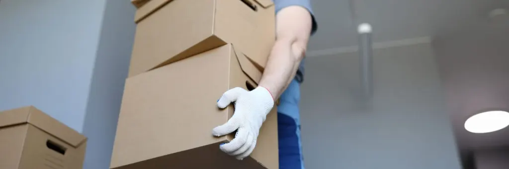 Addetto al facchinaggio solleva una pila di scatoloni