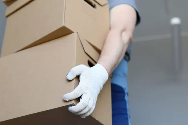Addetto al facchinaggio solleva una pila di scatoloni