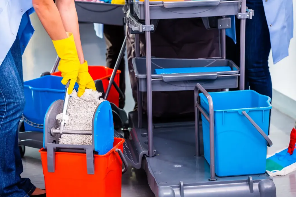 Operatori delle pulizie con carrello, secchi e mop
