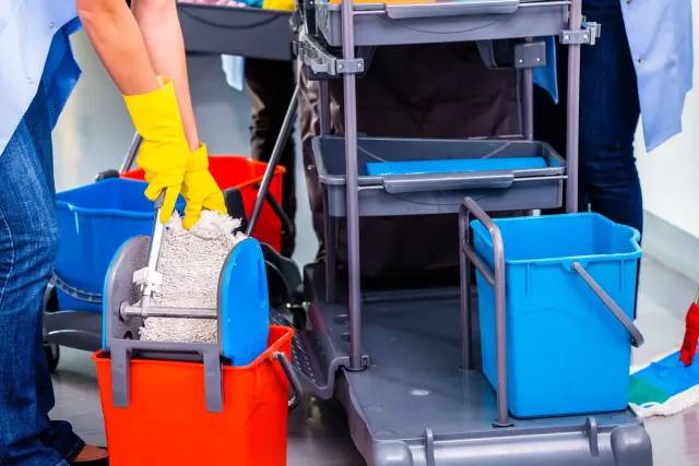 Operatori delle pulizie con carrello, secchi e mop