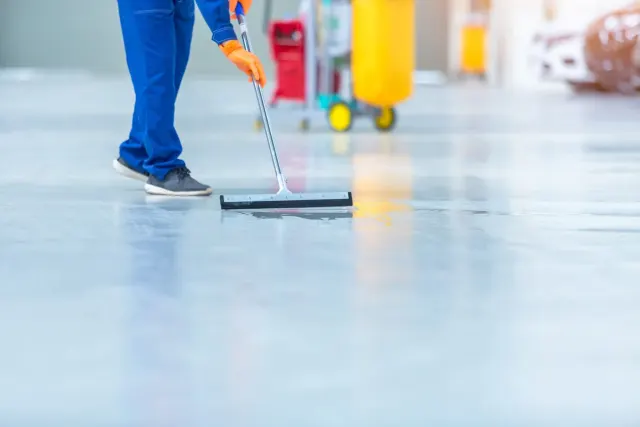 Operatore lava il pavimento di un capannone industriale